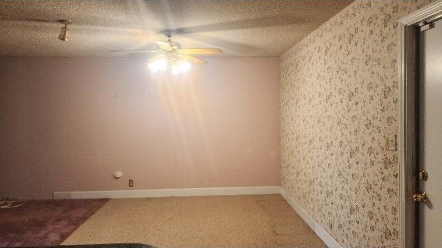 empty room with ceiling fan, carpet, and a textured ceiling