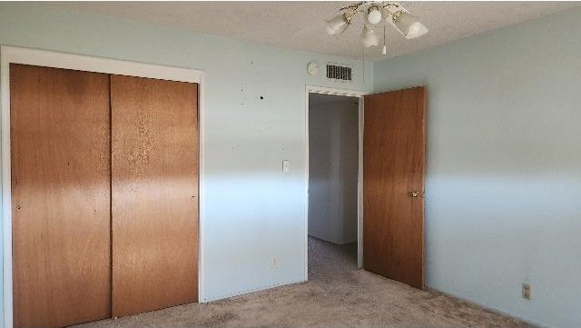 unfurnished bedroom with light carpet, ceiling fan, and a closet