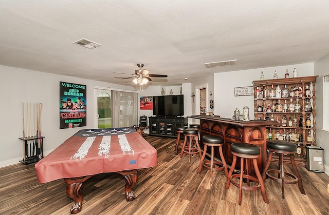 bar with ceiling fan, wood-type flooring, and a textured ceiling