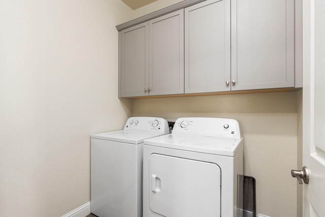 laundry room featuring washer and clothes dryer and cabinets