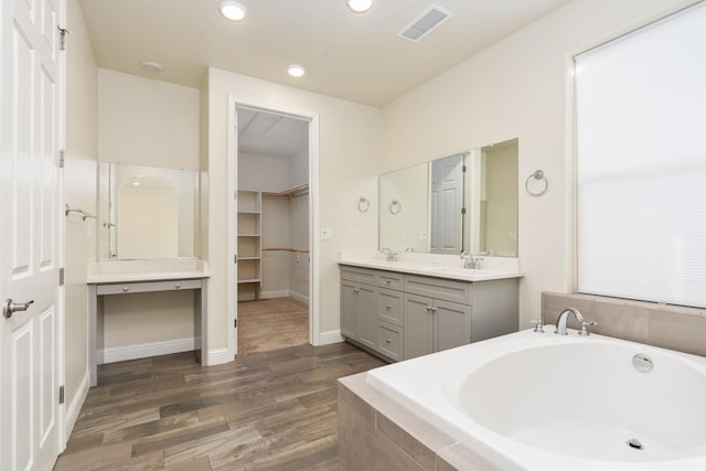 bathroom with vanity, wood-type flooring, and tiled bath