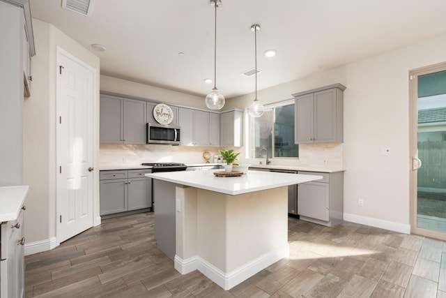 kitchen featuring a kitchen island, gray cabinetry, and decorative light fixtures