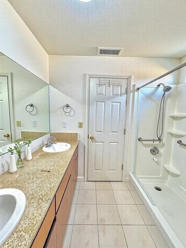 full bathroom with visible vents, a stall shower, a sink, a textured ceiling, and tile patterned floors