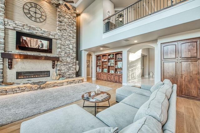 living room with a towering ceiling, built in features, and light hardwood / wood-style flooring