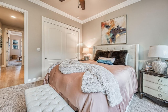 carpeted bedroom featuring ornamental molding, ceiling fan, and a closet