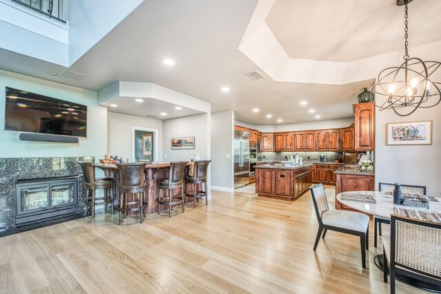 kitchen featuring a chandelier, hanging light fixtures, light hardwood / wood-style flooring, stainless steel built in fridge, and a kitchen island