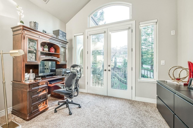 carpeted home office with lofted ceiling, a wealth of natural light, and french doors