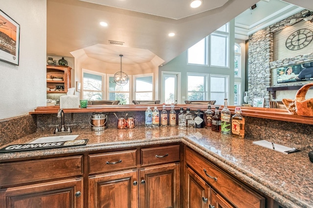 kitchen with pendant lighting, sink, dark stone countertops, and a chandelier