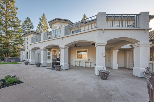 rear view of property with a balcony, ceiling fan, and a patio area