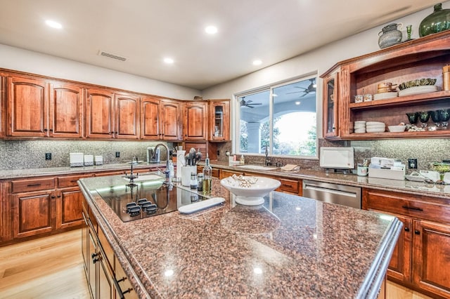 kitchen featuring dishwasher, dark stone countertops, a kitchen island with sink, and black electric stovetop