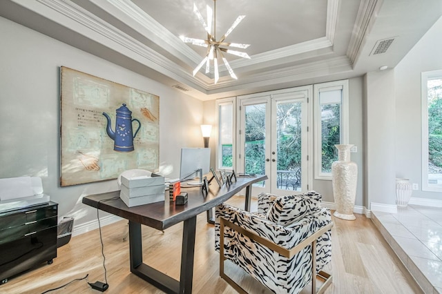 office space featuring crown molding, french doors, a raised ceiling, a chandelier, and light wood-type flooring