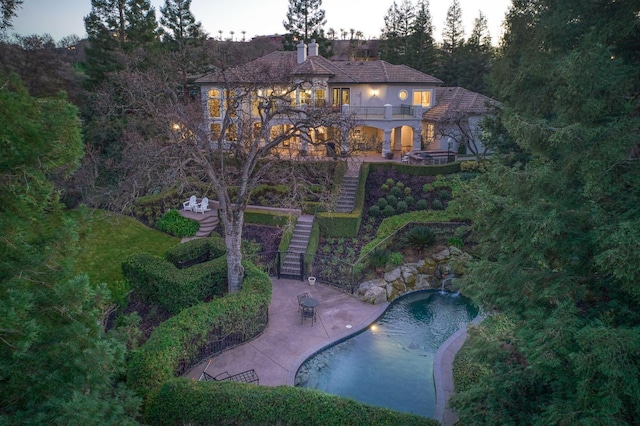 back house at dusk featuring a patio and a balcony