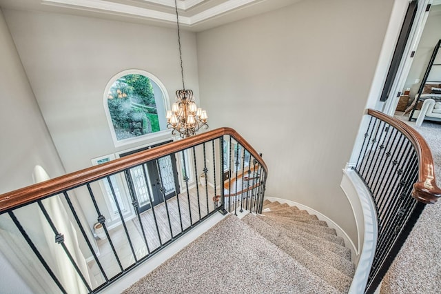 staircase featuring an inviting chandelier, a towering ceiling, and carpet