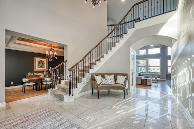 staircase featuring a tray ceiling, a towering ceiling, and a chandelier