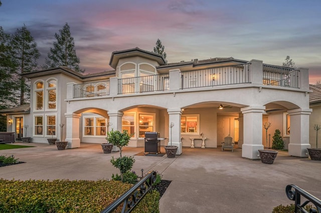 back house at dusk featuring a patio and a balcony