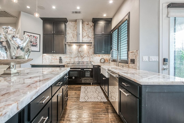 kitchen with sink, appliances with stainless steel finishes, pendant lighting, wall chimney range hood, and backsplash