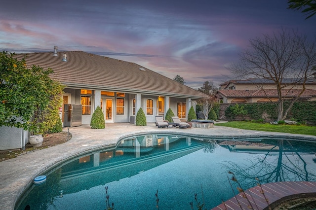 pool at dusk with a patio area