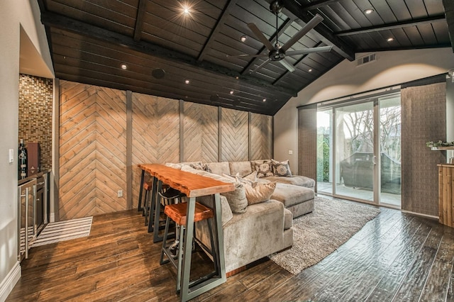 home theater with vaulted ceiling with beams, wooden walls, dark hardwood / wood-style floors, and ceiling fan