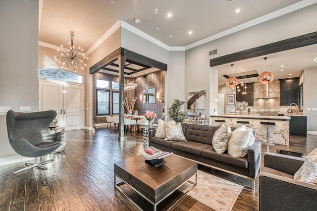 living room featuring ornamental molding, dark hardwood / wood-style floors, sink, and a chandelier