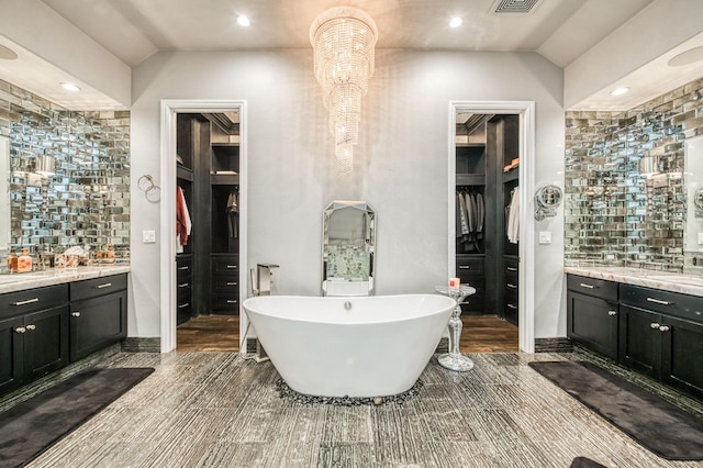 bathroom featuring tasteful backsplash, vanity, a bath, and vaulted ceiling