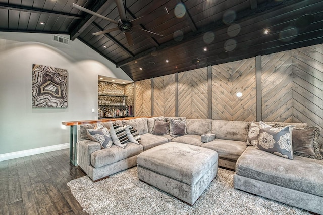 living room featuring wood walls, lofted ceiling with beams, indoor bar, hardwood / wood-style flooring, and ceiling fan