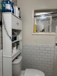 bathroom featuring toilet and tile walls