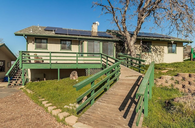 back of house with a wooden deck and solar panels