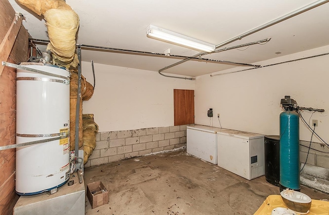 basement featuring water heater and refrigerator