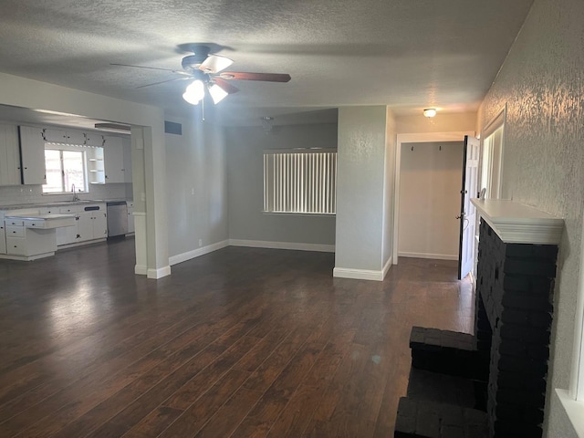 129 N Armstrong Ave, Fowler, CA 93625 - unfurnished living room with dark wood-style floors, a ceiling fan, a textured ceiling, a sink, and baseboards