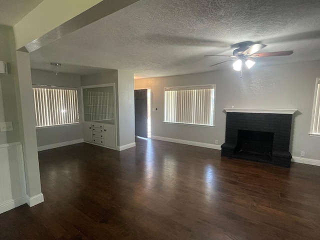 unfurnished living room with a brick fireplace, dark hardwood / wood-style floors, and ceiling fan