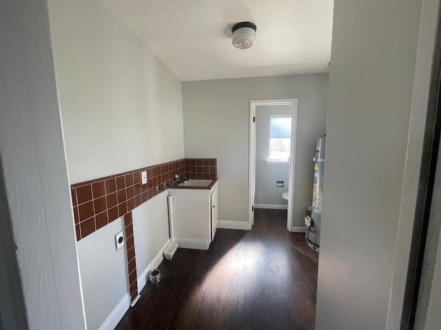 laundry room with dark hardwood / wood-style flooring, sink, and secured water heater