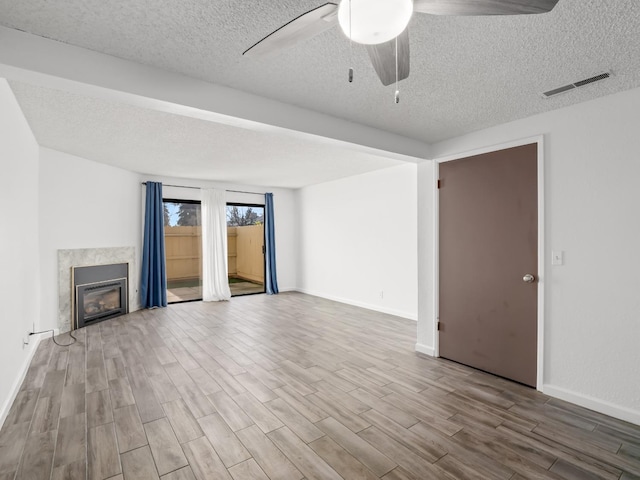 unfurnished living room with hardwood / wood-style flooring, ceiling fan, and a textured ceiling