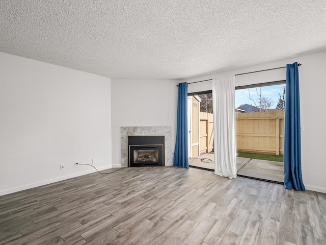 unfurnished living room with a textured ceiling, a high end fireplace, and light hardwood / wood-style floors