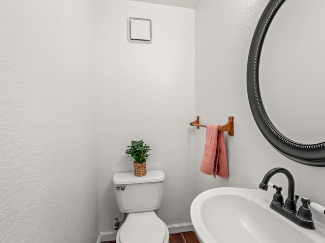 bathroom with wood-type flooring, toilet, and sink