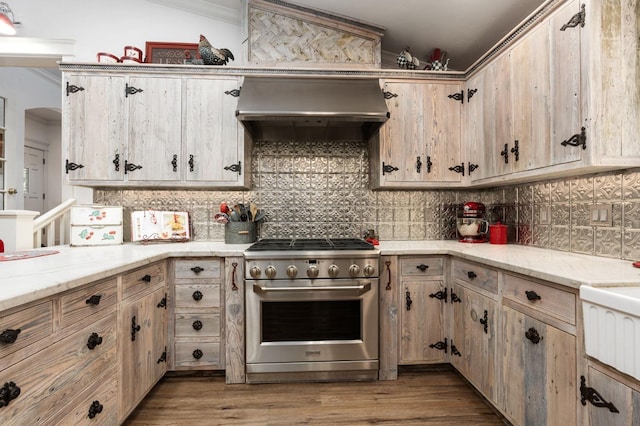 kitchen featuring premium range hood, light brown cabinetry, tasteful backsplash, stainless steel stove, and light hardwood / wood-style floors