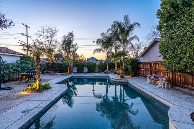 pool at dusk with a patio