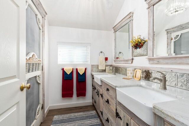 bathroom with vaulted ceiling, wood-type flooring, vanity, and backsplash