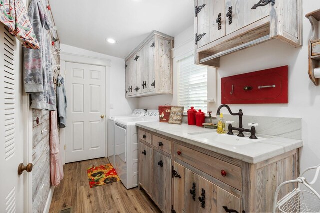 washroom featuring cabinets, sink, washer and clothes dryer, and light wood-type flooring