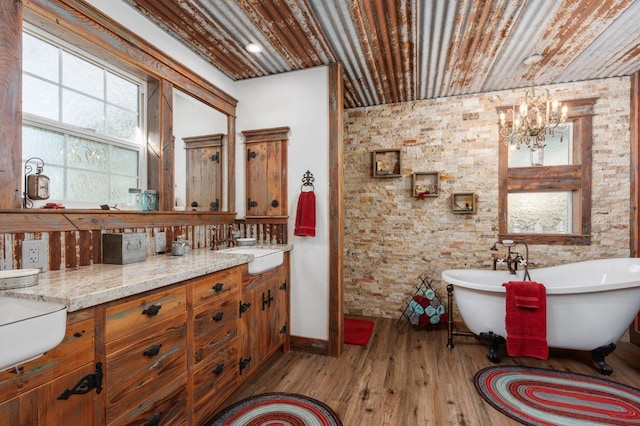 bathroom featuring hardwood / wood-style flooring, vanity, a chandelier, and a bathtub