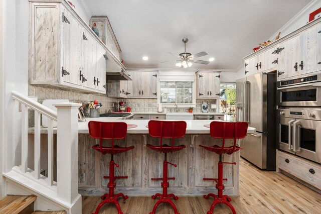 kitchen featuring ornamental molding, appliances with stainless steel finishes, a breakfast bar, and kitchen peninsula