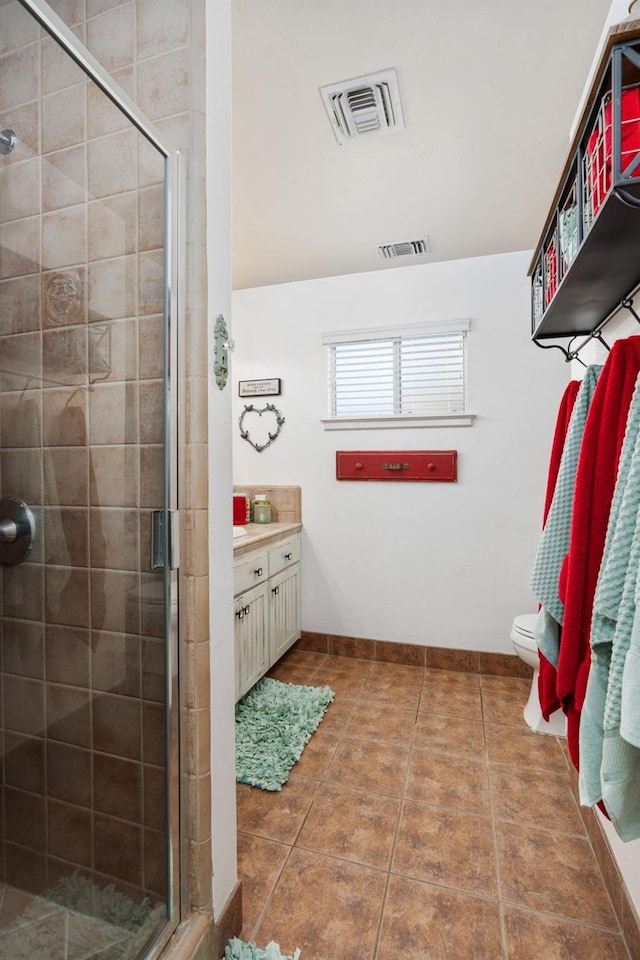 bathroom featuring vanity, tile patterned flooring, toilet, and walk in shower