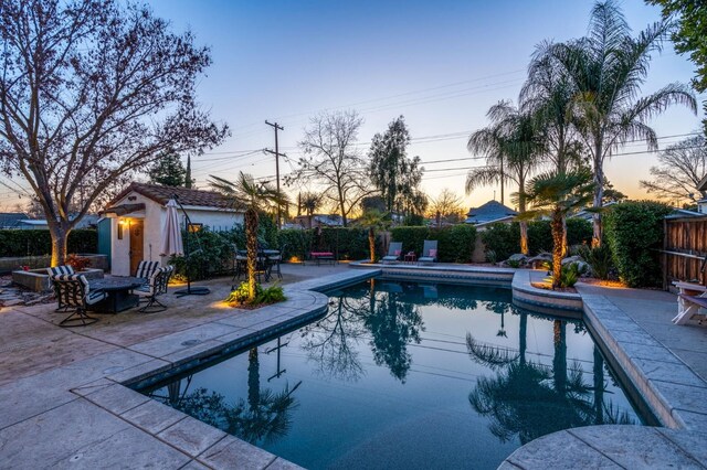 pool at dusk with a patio area