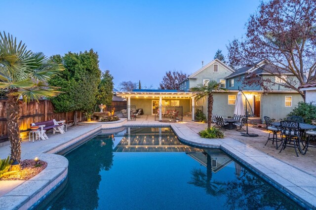 pool at dusk featuring a patio