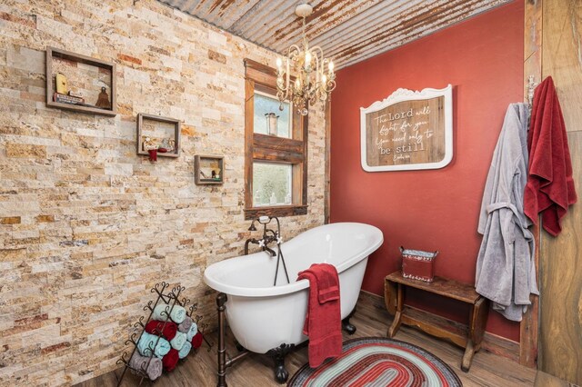 bathroom featuring hardwood / wood-style floors, brick ceiling, a washtub, and a chandelier