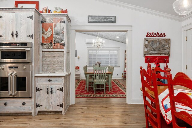 kitchen featuring an inviting chandelier, wood-type flooring, ornamental molding, vaulted ceiling, and stainless steel double oven