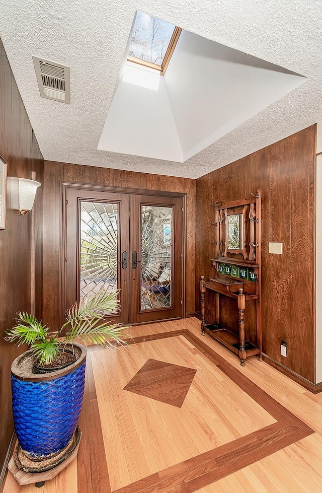3670 S Newmark Ave, Sanger, CA 93654 - entryway with wood finished floors, wood walls, french doors, a skylight, and a textured ceiling