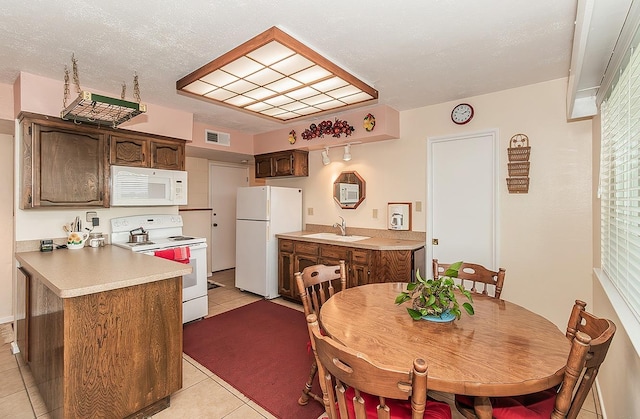 3670 S Newmark Ave, Sanger, CA 93654 - kitchen with white appliances, light tile patterned flooring, a peninsula, light countertops, and a sink
