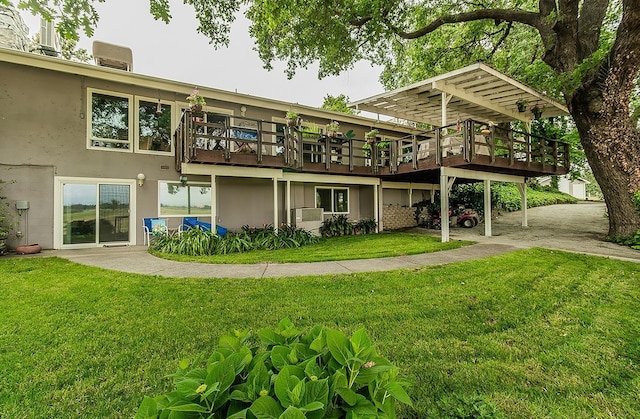 back of house featuring a yard, a wooden deck, and stucco siding