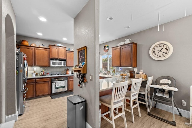 kitchen featuring stainless steel appliances, a kitchen bar, kitchen peninsula, and backsplash