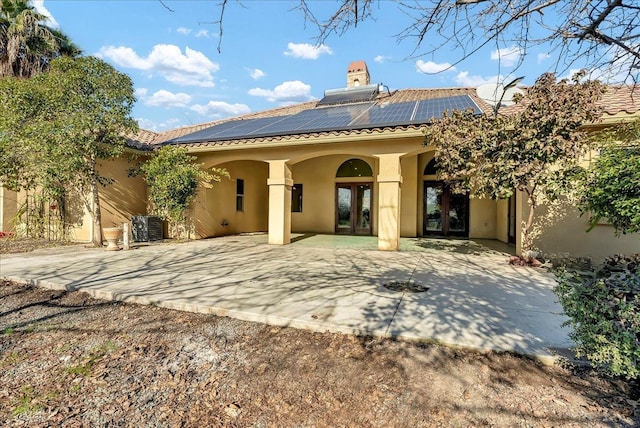 back of house with french doors, central AC unit, and solar panels